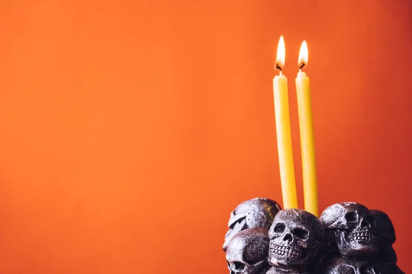 Crânes avec des bougies brûlant sur un fond de couleur orange. Espace libre pour le texte — Photo