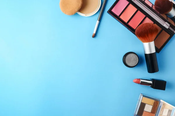 Ovanifrån av kosmetika som angetts för makeup på en blå bakgrund. Ledigt utrymme för text. — Stockfoto