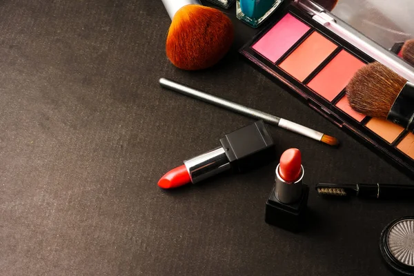 Ovanifrån av kosmetika som angetts för makeup på en svart bakgrund. Ledigt utrymme för text. — Stockfoto