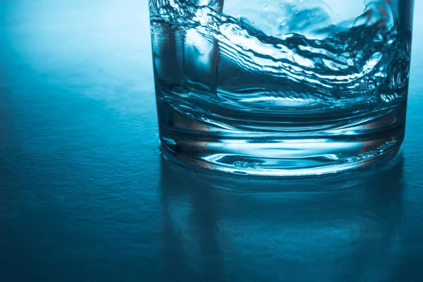 Gießen von Wasser in Glas auf blauem Hintergrund. — Stockfoto