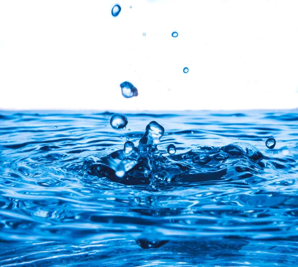 Salpicadura de gota de agua en la superficie del agua, ola azul y burbujas de fondo . — Foto de Stock