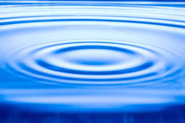 Goccia d'acqua sulla superficie dell'acqua, sfondo onda blu . — Foto Stock