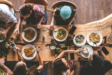 Bir grup mutlu arkadaş güzel yiyecekler ve içecekler yiyip içip eğleniyorlar, aile manzarası akşam yemeği yemek için evde toplanıyor..