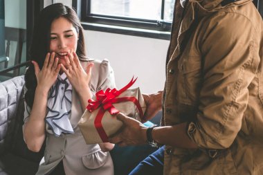 Onlar evde kanepede oturan genç adam bir hediye güzel kız arkadaşına veriyor