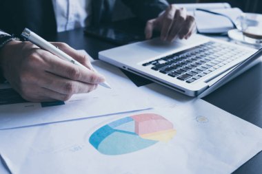 Dizüstü bilgisayar kullanarak ve ofis masasında yatırım grafikleri analiz işadamı yakın çekim.