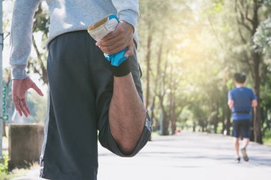 Bir adam bir parkta sabah çalıştırmadan önce germe