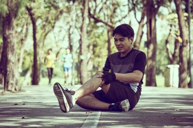 Asyalı bir adam bir parkta egzersiz yaparken diz ağrısı vardır.