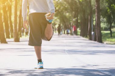 Bir adam bir parkta sabah çalıştırmadan önce germe