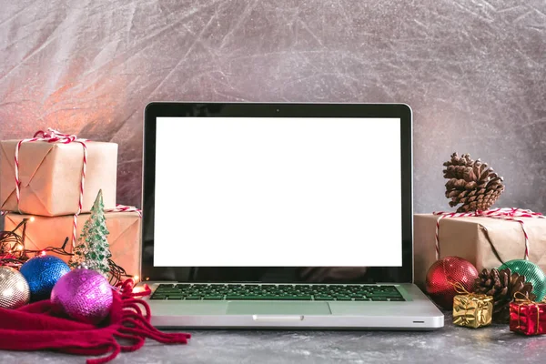 Ordenador portátil con pantalla blanca, cajas de regalo y decoración de Navidad en la mesa . — Foto de Stock