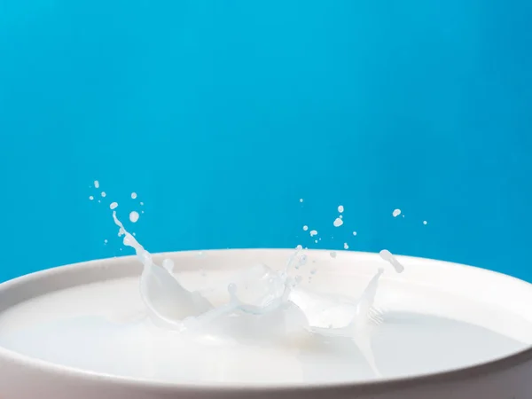 Розщеплення молока з чашки на синьому фоні . — стокове фото