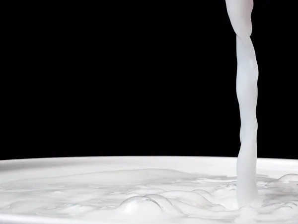 Розщеплення молока з чашки на чорному тлі . — стокове фото
