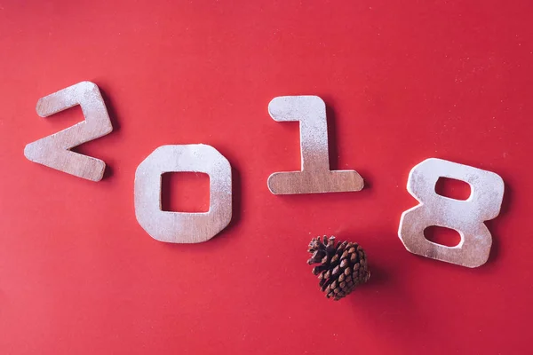 Números de madera 2018 con cono de pino sobre fondo rojo. Feliz Año Nuevo concepto — Foto de Stock