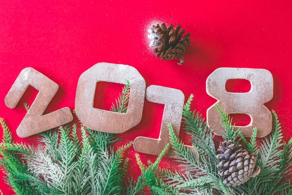 Números de madera 2018 con ramas de árbol de Navidad sobre fondo rojo. Feliz Año Nuevo concepto — Foto de Stock