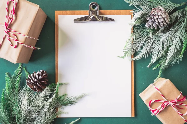Papel en blanco con cajas de regalo y ramas de árbol de Navidad sobre fondo verde . — Foto de Stock