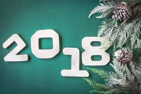 Números de madera 2018 con ramas de árbol de Navidad sobre fondo verde. Feliz Año Nuevo concepto — Foto de Stock