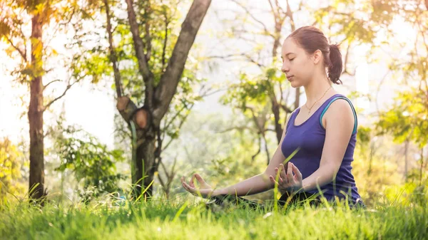 Hermosa mujer haciendo ejercicios de yoga en el parque. Concepto de estilo de vida saludable . — Foto de Stock