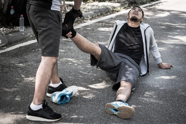 一个男人正在做伸展运动训练后, 他的朋友肌肉痉挛 — 图库照片
