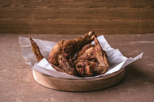 Gambe e ali di pollo fritte in piatto di legno sul tavolo . — Foto Stock