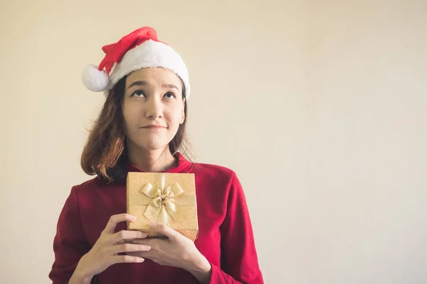 Happy Asian woman dressed in red Christmas hat holding gift box. — Stock Photo, Image