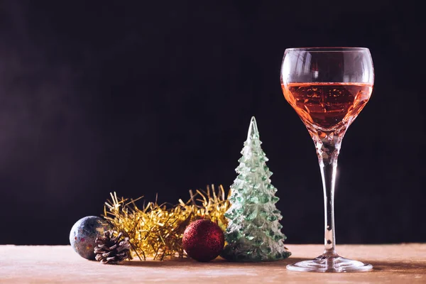 Copa de vino con decoraciones navideñas sobre la mesa de madera fondo negro, espacio libre para texto — Foto de Stock