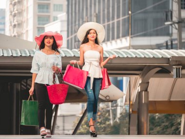 Alışveriş torbaları alışveriş zevk mutlu genç kadınlarla, Asyalı kız kendi alımları ile şehirde eğleniyorlar. Tüketicilik ve yaşam tarzı kavramı