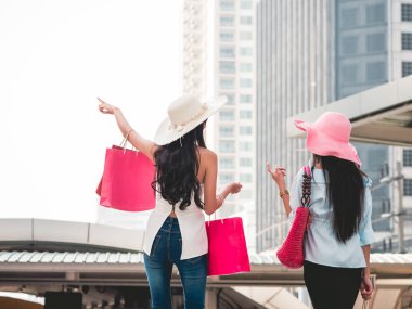 Arkadan Görünüm alışveriş torbaları alışveriş zevk olan genç kadın Asyalı kız kendi alımları ile şehirde eğleniyorlar. Tüketicilik ve yaşam tarzı kavramı