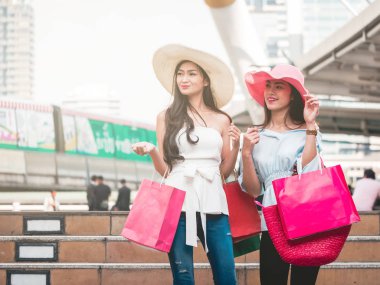 Alışveriş torbaları alışveriş zevk mutlu genç kadınlarla, Asyalı kız kendi alımları ile şehirde eğleniyorlar. Tüketicilik ve yaşam tarzı kavramı
