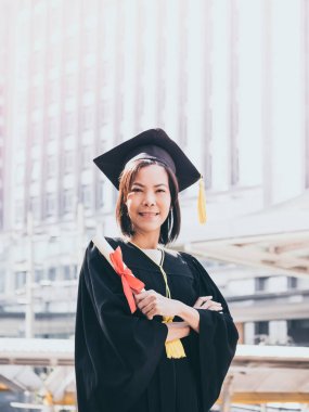 Mezuniyet günü, mezuniyet kapağı ve cüppe holding diploma, başarılı konsepti ile Asyalı kadın