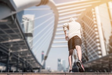 Arkadan görünüş atletik gencin şehir köprüsü üzerinde Bangkok kentsel sahne arka plan ile sabah koşan sportif adam koşu