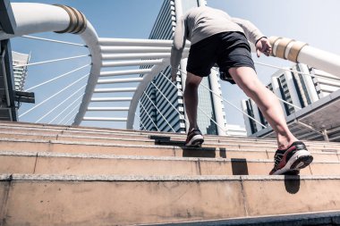 Arkadan görünüş atletik gencin şehir köprüsü üzerinde Bangkok kentsel sahne arka plan ile sabah koşan sportif adam koşu