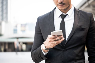 Kentsel sahne arka plan ile akıllı telefon kullanarak iş adamı yakın çekim.