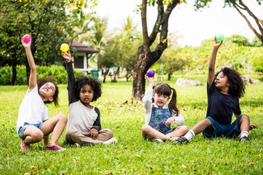 Topları birlikte oynayan çocuklar. Çim bir parkta oturan çocuk grup.