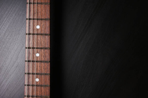 Close up of Electric guitar neck fingerboard on a black background. Free space for text