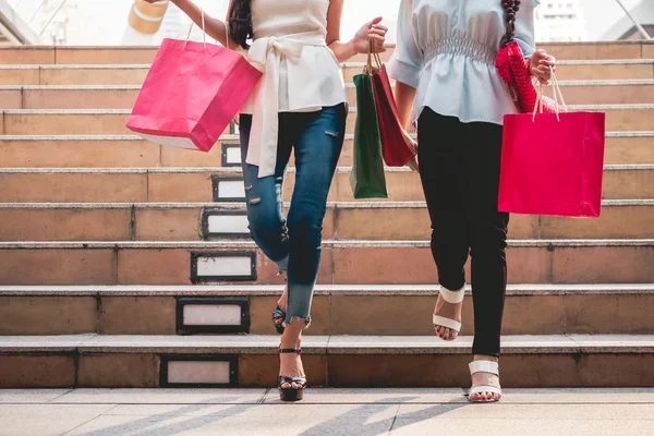 Primer plano de las mujeres con bolsas de compras disfrutando en las compras, Dos chicas se están divirtiendo con sus compras en la ciudad. Concepto de consumo y estilo de vida —  Fotos de Stock