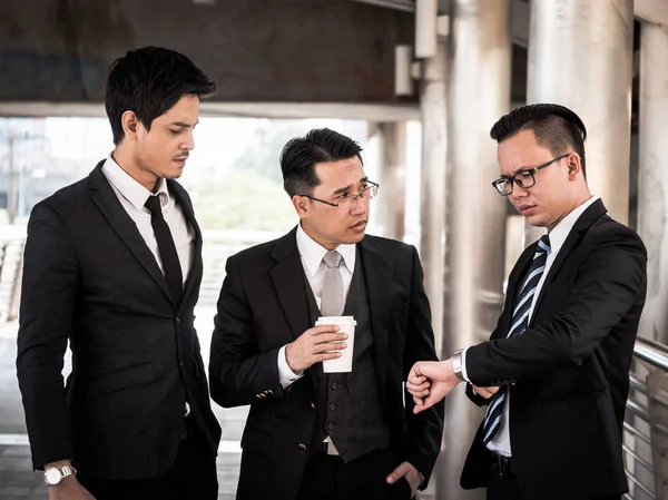 Les gens d'affaires asiatiques parlent ensemble avec le sentiment de stress tout en se tenant devant l'immeuble de bureaux . — Photo