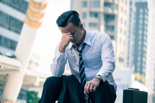 Frustrierter asiatischer junger Geschäftsmann sitzt vor dem Bürogebäude. — Stockfoto