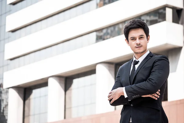 Retrato de un joven empresario asiático en traje negro de pie con fondo de edificio de oficinas. Espacio libre para texto — Foto de Stock