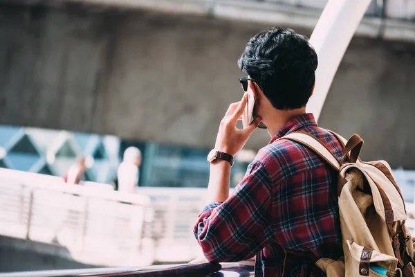 Случайный молодой азиат с рюкзаком разговаривает по мобильному телефону в городе . — стоковое фото