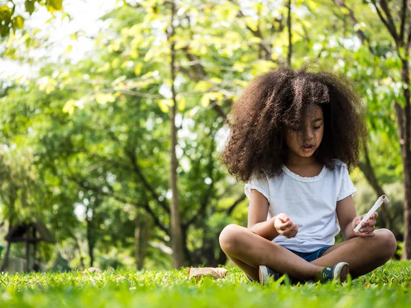 Hermosa chica sentada sobre hierba verde en un parque — Foto de Stock