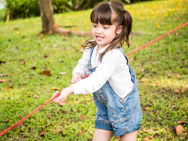 Una niña jugando a tirar de la guerra en un parque — Foto de Stock