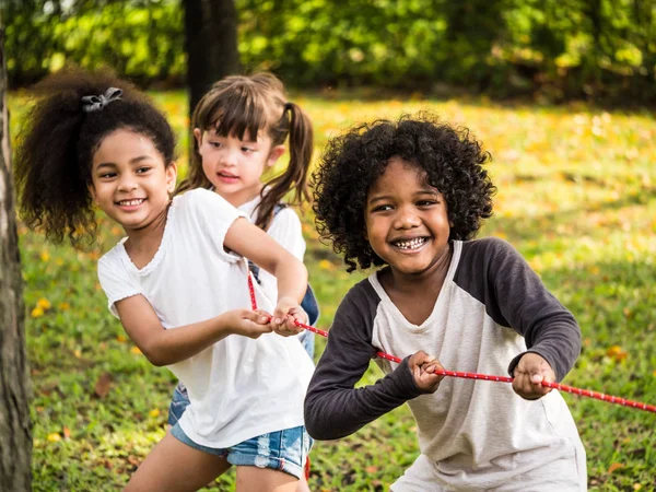 Heureux groupe d'enfants jouant remorqueur de guerre dans un parc — Photo