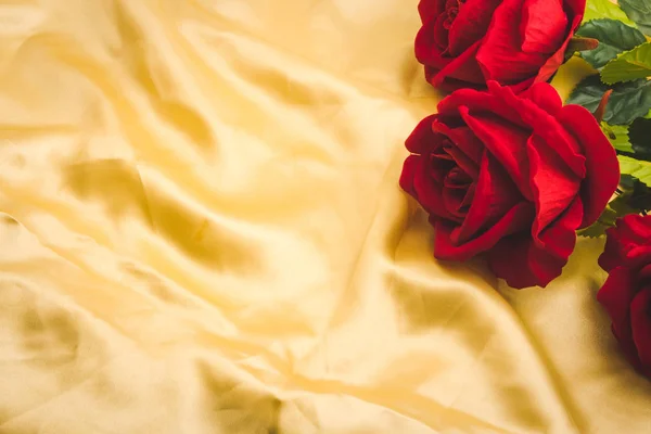 Bando de rosas vermelhas em fundo de tecido dourado. Espaço livre para texto Imagem De Stock