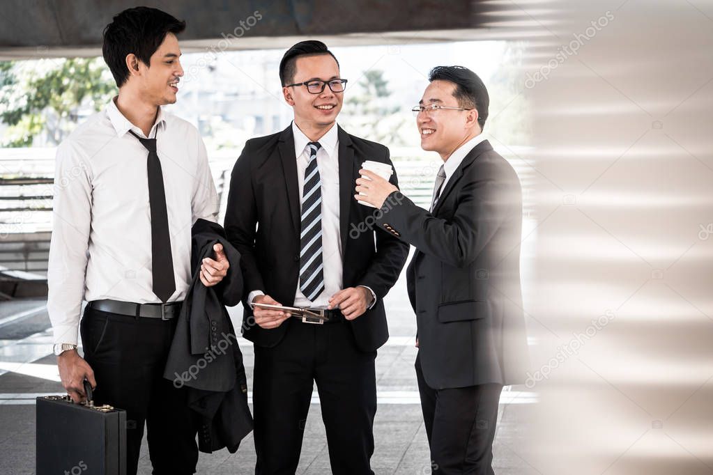 Group of business colleagues chatting during conference coffee break. Asian business men talking together while standing in front of the office building.