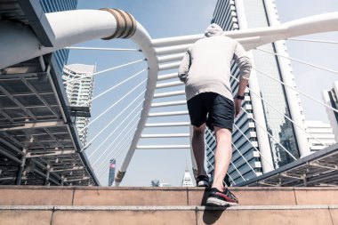 Arkadan görünüş atletik gencin şehir köprüsü üzerinde Bangkok kentsel sahne arka plan ile sabah koşan sportif adam koşu