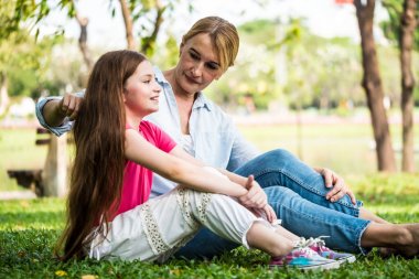 Anne ve kızı bir parkta çimlerin üzerine oturmuş rahatlatıcı. Aile ve yaşam tarzı kavramı