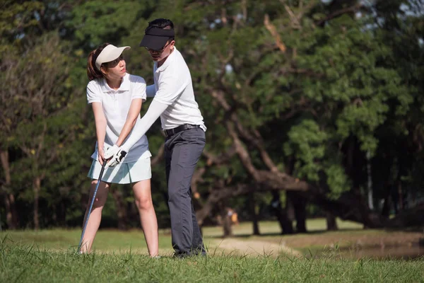 Asiático jovem casal jogar golfe no campo de golfe, o parceiro masculino é treinador para o golfista feminino — Fotografia de Stock