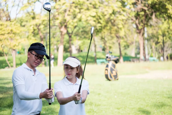 Asiático jovem casal jogar golfe no campo de golfe, o parceiro masculino é treinador para o golfista feminino — Fotografia de Stock