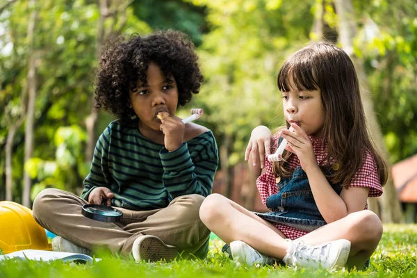 Gyerekek játszanak együtt a zöld gyep a parkban ülve — Stock Fotó
