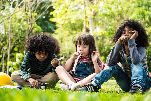 Niños jugando juntos mientras están sentados sobre hierba verde en un parque — Foto de Stock