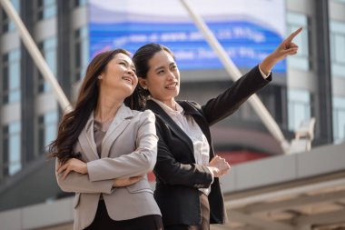 İşaret ve kentsel sahne arka plan ile gülümseyen iki Asya iş kadınları. Amaç ve başarı kavramı